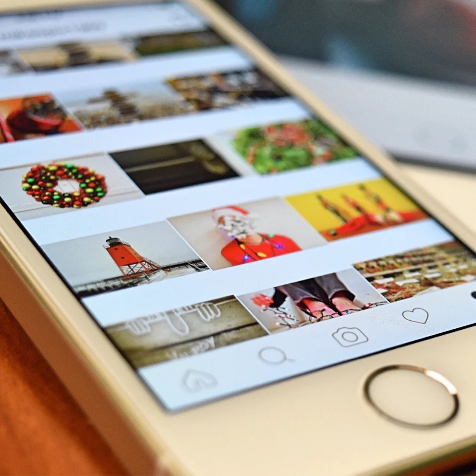Smartphone screen showing a social media photo grid with holiday-themed images, including decorations and a Santa figure