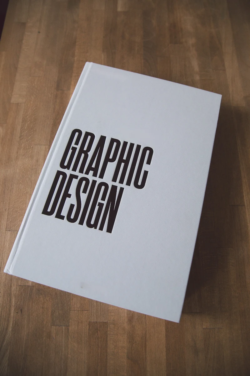 White hardcover book titled 'Graphic Design' placed on a wooden surface