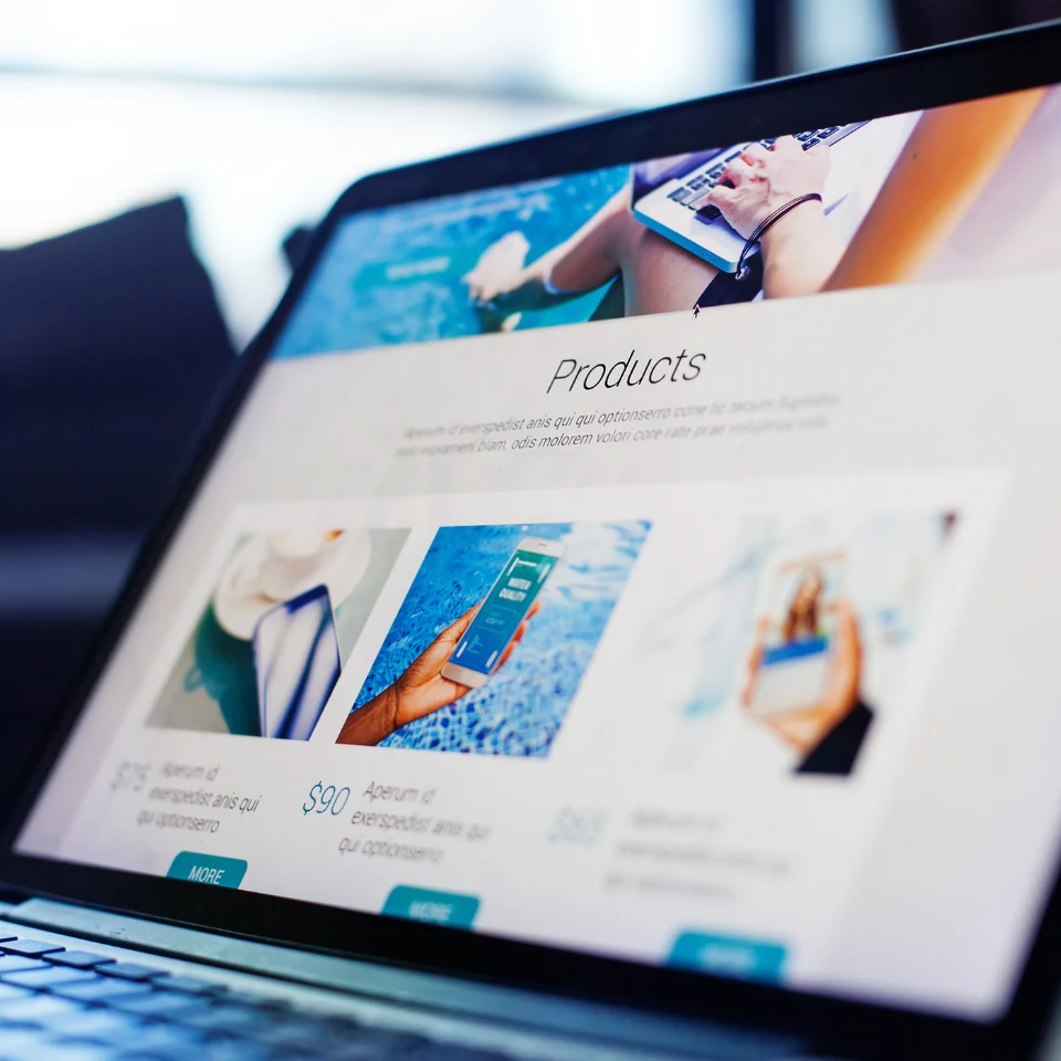 Laptop screen showing product webpage with smartphone images and 'Products' heading, displaying e-commerce website design