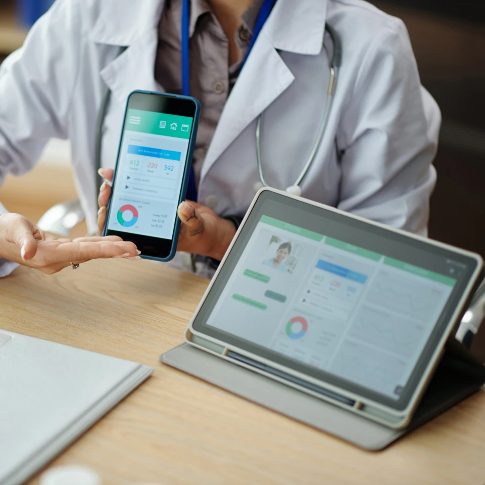 Hand holding smartphone displaying HealthCare app with pink heart icon, hand symbol, and Continue button on wooden background.