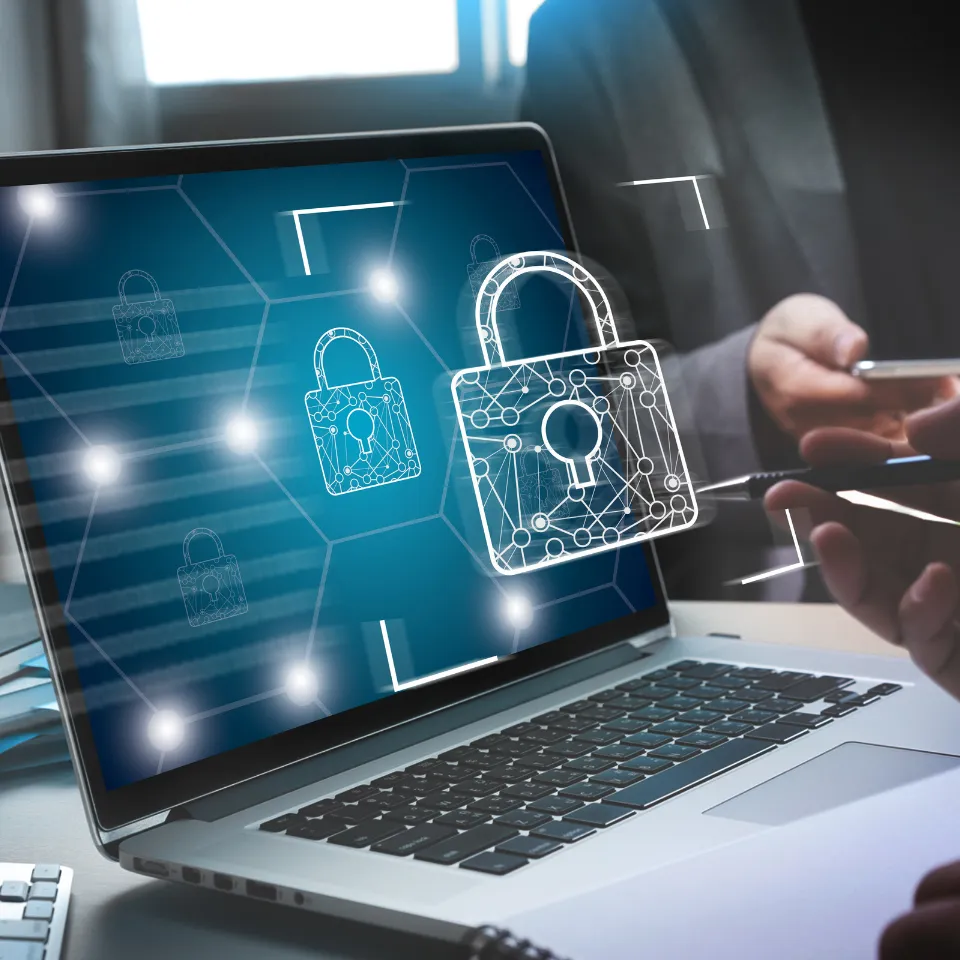 Laptop screen with digital security padlock icons and person holding smartphone, representing cybersecurity and data protection